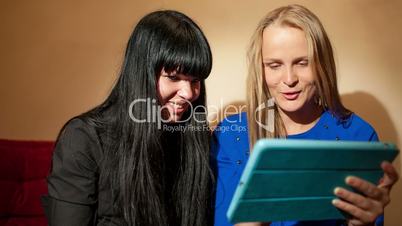 Two young woman reading a tablet-pc