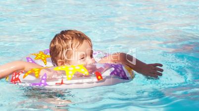 Kid learns to swim using a plastic water ring