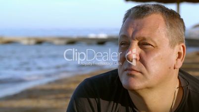 handsome middle-aged man thinking at the beach