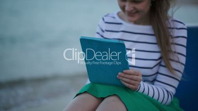 Young woman using tablet PC by the sea