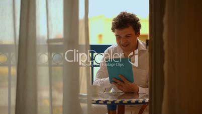 Man with laptop having tea on the balcony