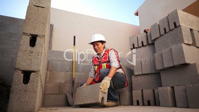 Woman Lifts Brick on Construction Site