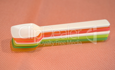 Colorful plastic spoons on a pink background