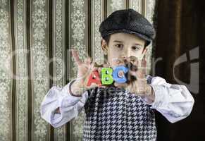 Child in vintage clothes hold letters a b c