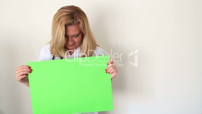woman holding onto a green screen and smiling