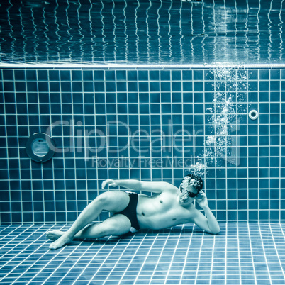 Persons lies under water in a swimming pool