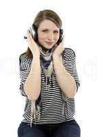 beautiful young smiling woman listens to music with headphones on her head