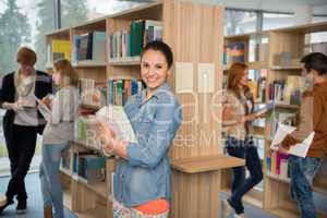 student holding books in library