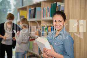 student holding books in university library