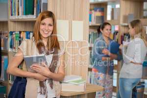 smiling college student holding tablet in library