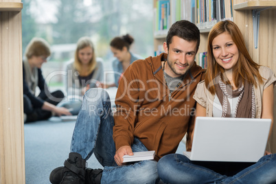 smiling college students with laptop in library