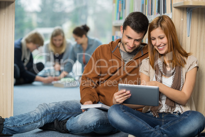 smiling students using tablet with in library