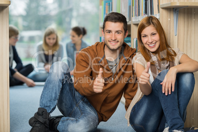 happy students showing thumb up in library