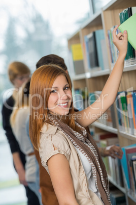 student taking book from bookshelf in library
