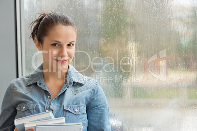 student with books in front of window