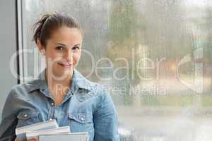 student with books in front of window