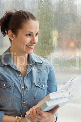 student holding books by wet window