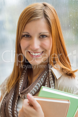student holding books in front of window
