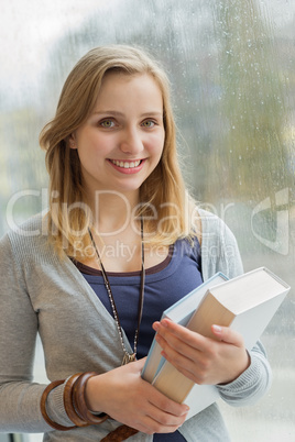 happy student holding books by window