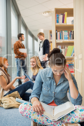 girl reading book in college library