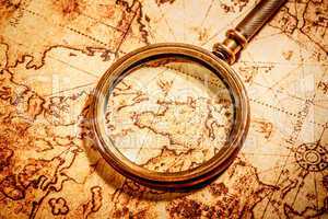 vintage magnifying glass lies on an ancient world map
