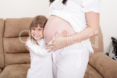 smiling girl listening to the abdomen of her mother. smiling girl listening to the abdomen of her mother.