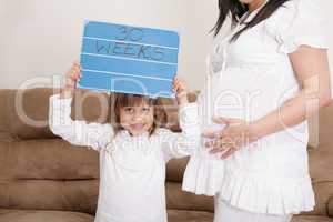 girl holding a 30 weeks sign to her expectant mother