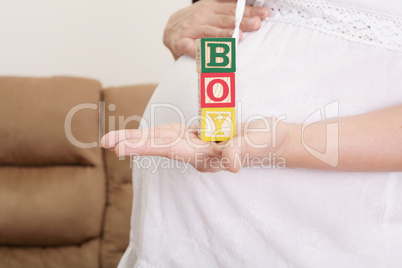 pregnant woman having the word "boy" with wooden blocks written