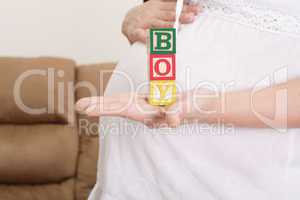 pregnant woman having the word "boy" with wooden blocks written