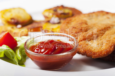 Ketchup mit einem Wiener Schnitzel und Bratkartoffeln