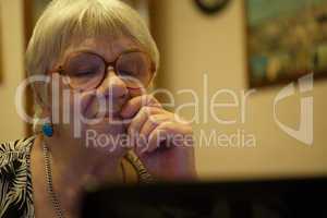 thoughtful senior woman reading a computer screen