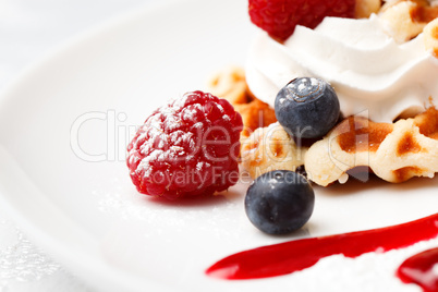 golden waffle served with cream and berries