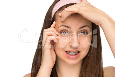 worried girl with braces squeezing pimple isolated