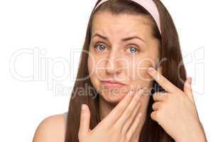 unhappy girl squeezing pimple on cheek isolated