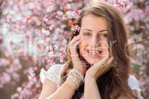 romantic girl with braces near blossoming tree