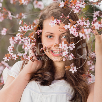girl with braces holding blossoming tree branch