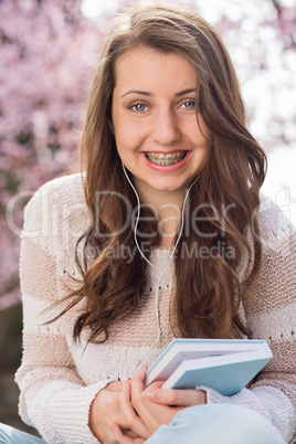 student with braces holding book outside