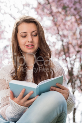 student reading book near blossoming tree spring