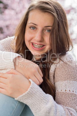 girl with braces hugging knees in nature