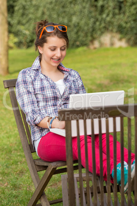 smiling girl using laptop sitting at park