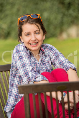 girl with braces hugging knees at park