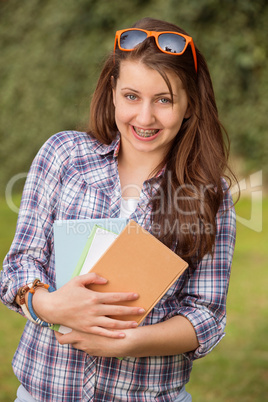 happy student with braces holding books outside