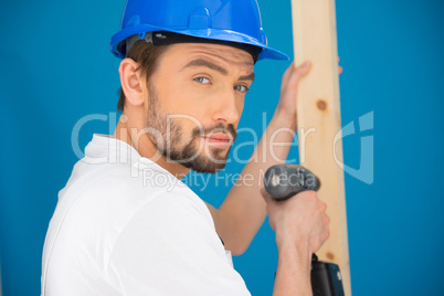 Builder using a drill looking at the camera