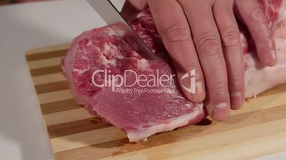 Male hands cutting raw pork meat