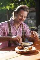 Attractive man eats traditional cheese in a Bavarian beer garden