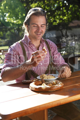 Attractive man eats traditional cheese in a Bavarian beer garden