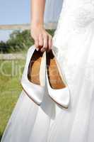 Bride holds bridal shoes in hand