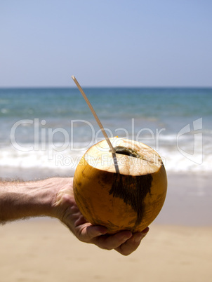 Man holding coconut drink with straw in hand
