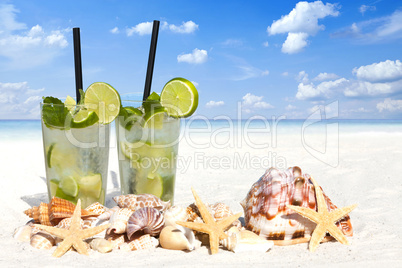 Eiskalter Mojito Cocktail und Muscheln am Sandstrand