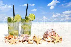 Eiskalter Mojito Cocktail und Muscheln am Sandstrand